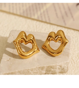 Macro view of 18k gold plated stainless steel hollow lip earrings on white stone