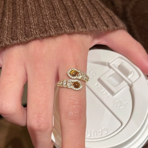 Detail of gold open ring with brown tiger eye stones and zircon accents on finger