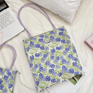 Dettaglio della borsa tote in tela floreale con sottili spalline in PU viola e astuccio