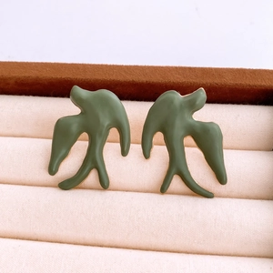 Macro shot of dark green swallow stud earrings in a velvet jewelry display box