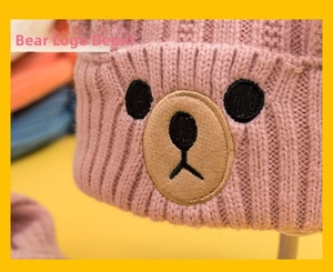 Close-up of pink cable knit hat featuring a cute embroidered teddy bear patch detail