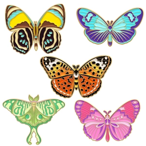 Detail of five colorful butterfly and moth enamel pins with golden metal outlines