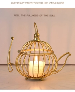Detail of a golden teapot-shaped metal candle holder with a white pillar candle inside