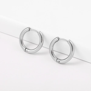 Macro shot of silver geometric huggie hoop earrings on a minimalist white background