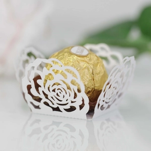 Close-up of white laser-cut rose hollow paper chocolate liners for wedding dessert decor