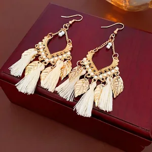 Bohemian leaf tassel earrings with gold metal frame and white silk fringe on wood box