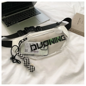 Détail du sac bandoulière en PVC transparent avec logo noir et pendentif à carreaux