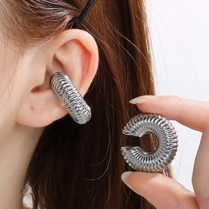 Macro shot of silver C-shaped hollow ribbed hoop earring showing glossy metal texture