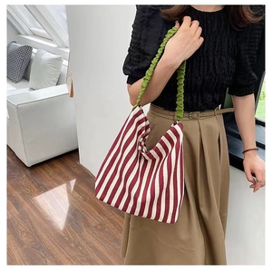 Detail of red and white striped tote bag with contrasting light green pleated shoulder strap