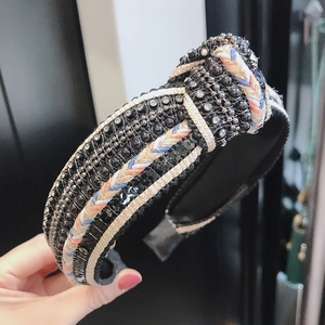 Detail of hand-held knotted velvet headband with sparkling sequins and woven rope trim