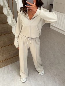 Détail d'un survêtement beige avec veste à capuche zippée et pantalon large à cordon