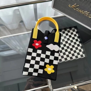 Détail du sac de téléphone en tricot avec motif en damier et broderies de fleurs