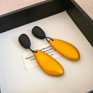 Detail of vintage teardrop earrings in matte black and yellow wood on a display box