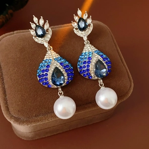 Dettaglio di orecchini vintage con cristalli blu e perle bianche su velluto