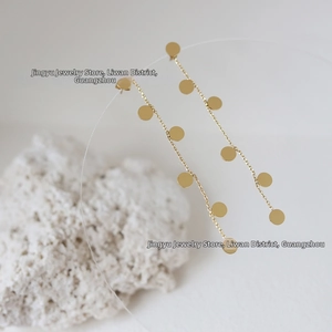 Macro detail of long gold drop earrings with circular discs on 18K gold plated steel