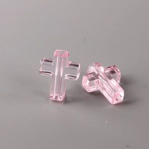 Macro detail of two translucent pink cross beads with vertical holes for DIY jewelry