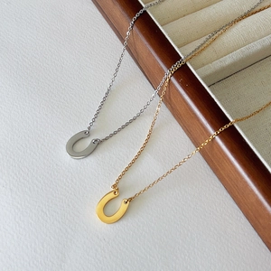 Macro detail of U-shaped horseshoe pendant necklaces in gold and silver finish
