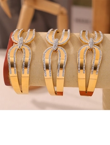 Détail de trois bracelets en titane plaqué or 18k avec strass pavés sur velours beige