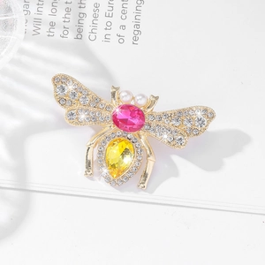 Detailed view of luxury bee brooch with pink and yellow gemstones on a book