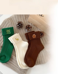 Detailed close-up of knit Christmas socks featuring festive cat, elk, and bear embroidery