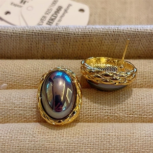 Macro detail of 18K gold-plated oval pearl earrings with vintage braided texture edges