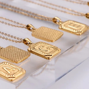 18k gold plated rectangular letter necklace with diamond cut pattern on acrylic stand