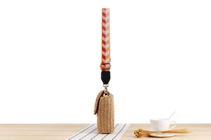 Detailed close-up of handmade woven straw bag with colorful geometric strap and gold clasp