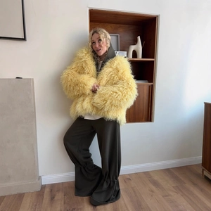 Oversized bright yellow faux mink fur hooded jacket for women styled with dark trousers