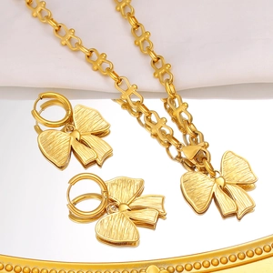 Detailansicht von goldenem Schleifen Halsketten und Ohrring Set auf weißer Seide
