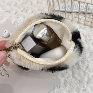 Macro detail of plush heart coin purse with cow print pattern and metal zipper closure