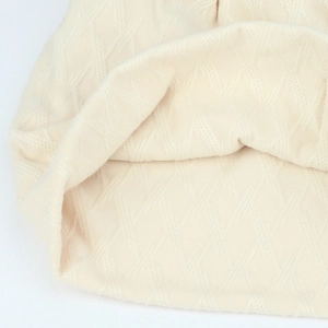 Macro detail of the diamond knit texture and premium stitching on the cream beanie