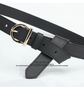 Detail of a thin black leather belt featuring a polished gold horseshoe buckle and pin