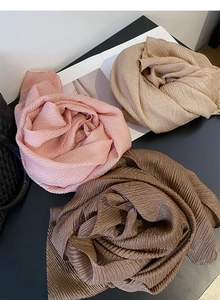 Dettaglio delle sciarpe a trama increspata in rosa, beige e marrone con finitura lucida