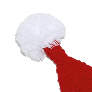 Macro detail of red knit Christmas hat showing soft white pompom and yarn texture