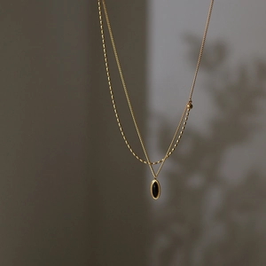 Gros plan du collier doré double rang avec pendentif ovale noir vintage sur fond gris