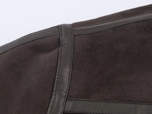 Detailed macro view of dark brown faux suede fabric with leather piping on the jacket