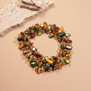 Detail of bohemian layered necklace featuring green and amber faceted glass beads