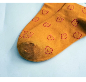 Detailed close-up of yellow cotton socks featuring cute pink cartoon bear patterns