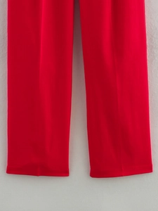 Détail du pantalon rouge à coupe droite montrant le tissu tissé lisse et le drapé
