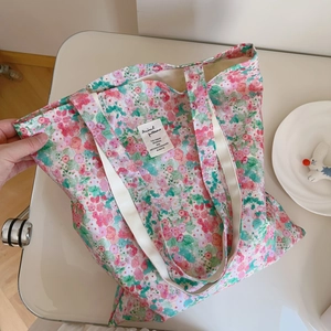 Close-up of pink floral tote bag fabric with white canvas straps and text label