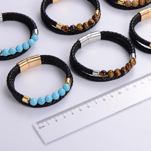 Pulsera de hombre de cuero trenzado con cierre magnético y cuentas ojo de tigre junto a una regla