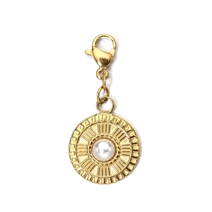 Macro shot of gold circular pendant with pearl inlay and lobster clasp on white background