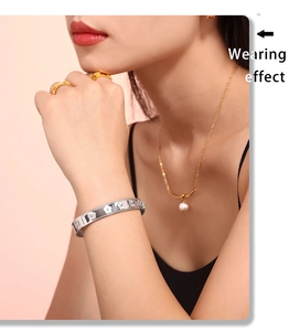 Dettaglio del bracciale argento floreale a rilievo con collana di perle dorate su modella