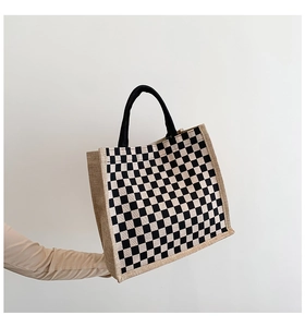 Macro view of checkered jute tote bag showing coarse texture and black fabric handle
