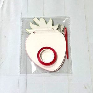 Detail of strawberry paper cutouts with red ribbon and needle for party banner DIY kit