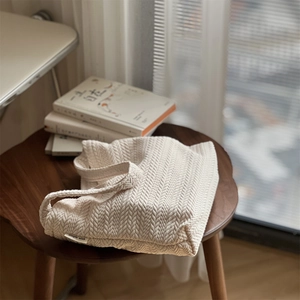 Chic beige woven knit tote bag with rice spike texture on a wooden stool setup