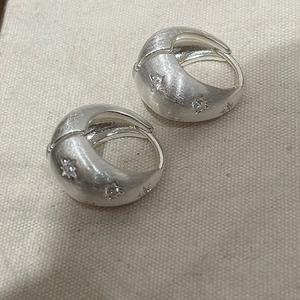 Detail of brushed silver star earrings featuring sparkling cubic zirconia stones