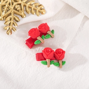 Detailed view of two red rose hair clips with green leaves on red ribbon bases