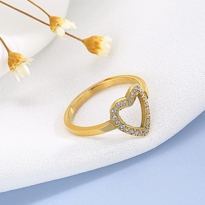 Detail of hollow heart-shaped gold ring micro-set with white zircon on a soft fabric base