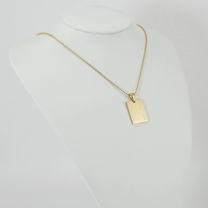 Golden stainless steel square tag necklace with Breathe engraving on a white mannequin